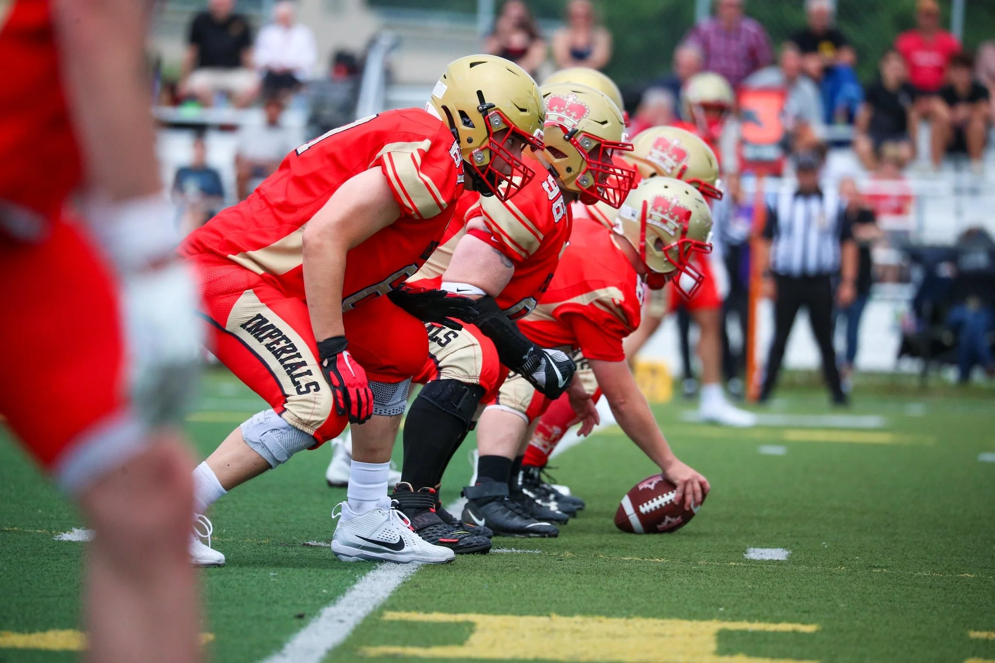 American football players in red and gold uniforms in a formation on the field, ready for a play.