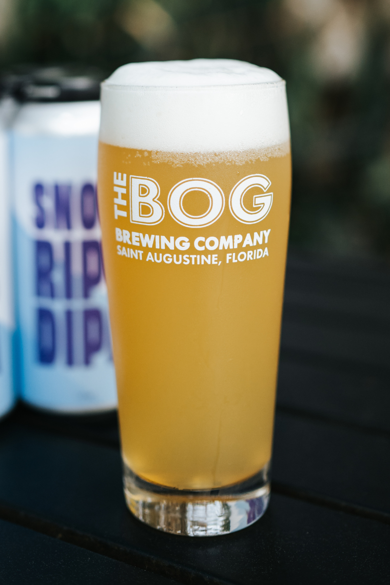 A double hazy IPA in a glass with a mug that features the state of Florida.