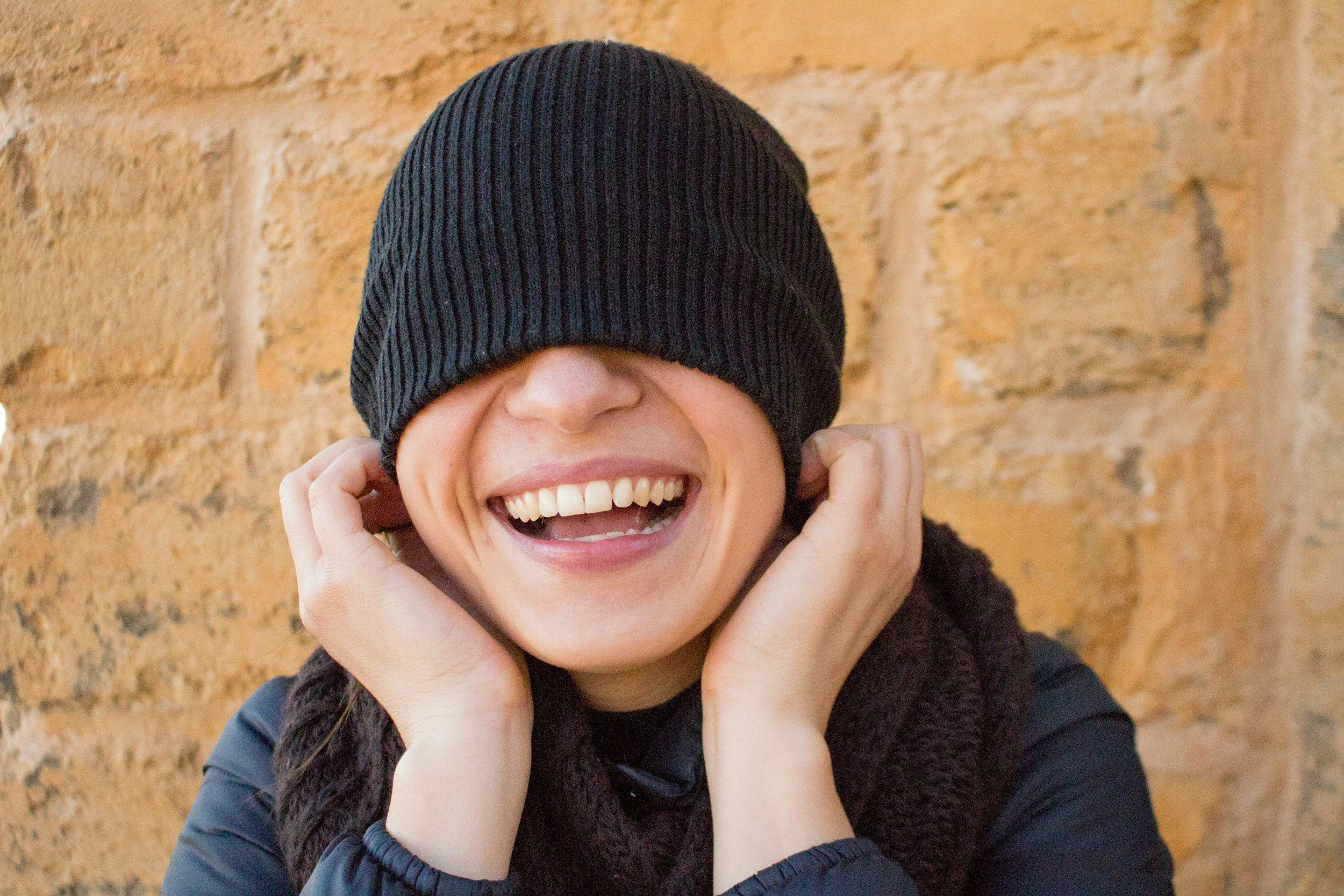 Person laughing with a hat covering their eyes, symbolizing life beyond anxiety, emotional resilience, renewed confidence, nervous system regulation, and healing through somatic coaching.