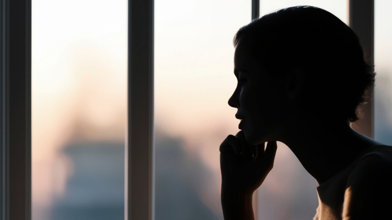 Person reflecting by a window, representing self-discovery, emotional clarity, nervous system regulation, and support through somatic coaching.