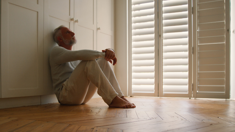 Person sitting thoughtfully indoors, symbolizing self-criticism, harsh self-talk, perfectionism, self-doubt, emotional healing, self-awareness, and personal growth through somatic coaching.