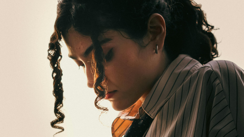 Person looking downward in quiet reflection, representing self-criticism, negative self-talk, perfectionism, self-doubt, self-awareness, and personal growth through somatic coaching.