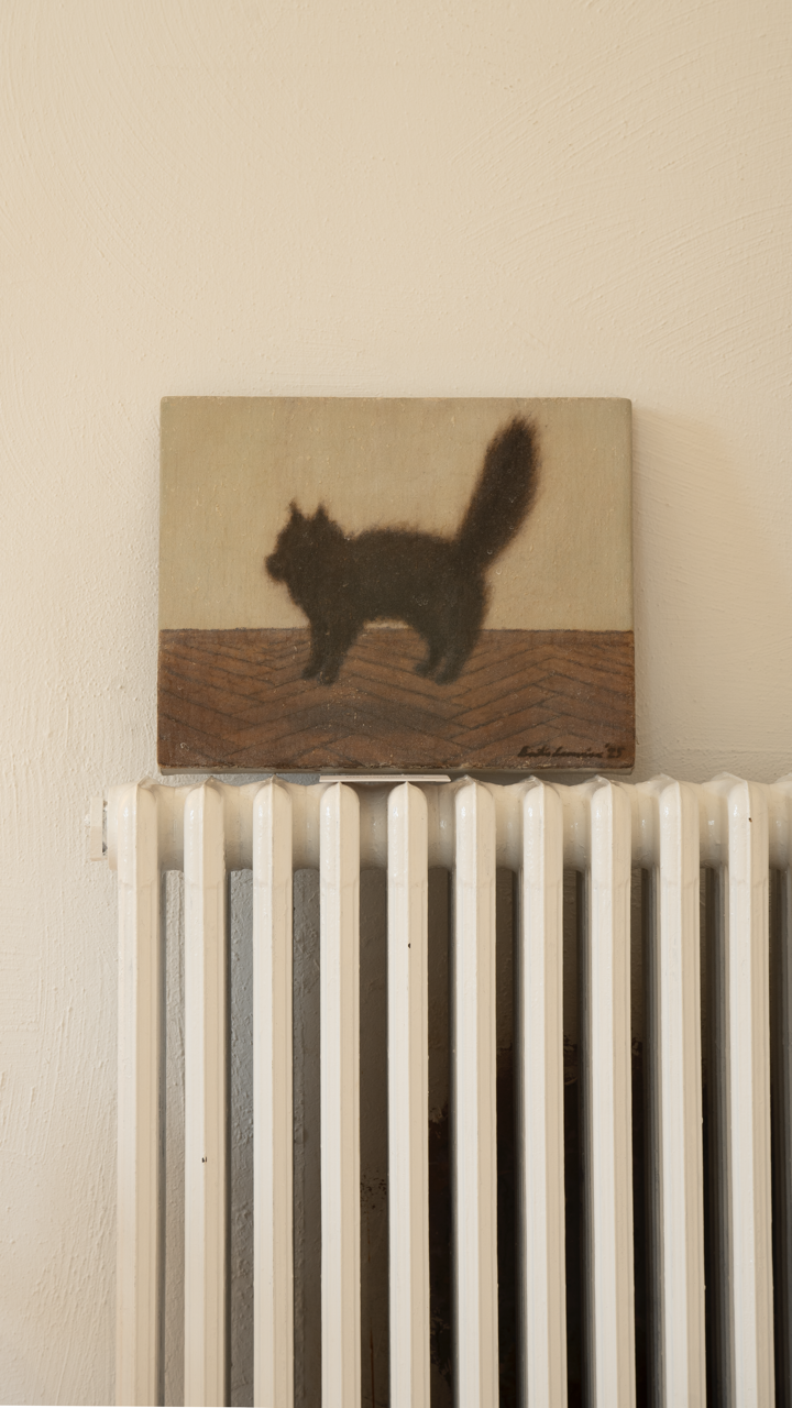 Elle – Chat noire by Emilia Lemaire, 2025. A startled black cat in mid-leap above a herringbone parquet floor, its body stiff, its fur and tail bristling, against a pale wall. The painting rests on a white radiator.