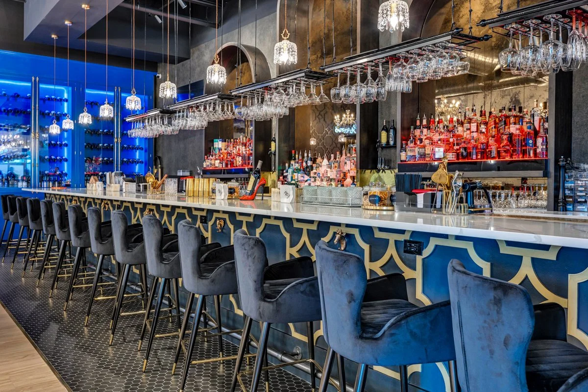bar area with black velvet chairs, chandeliers, gold accents