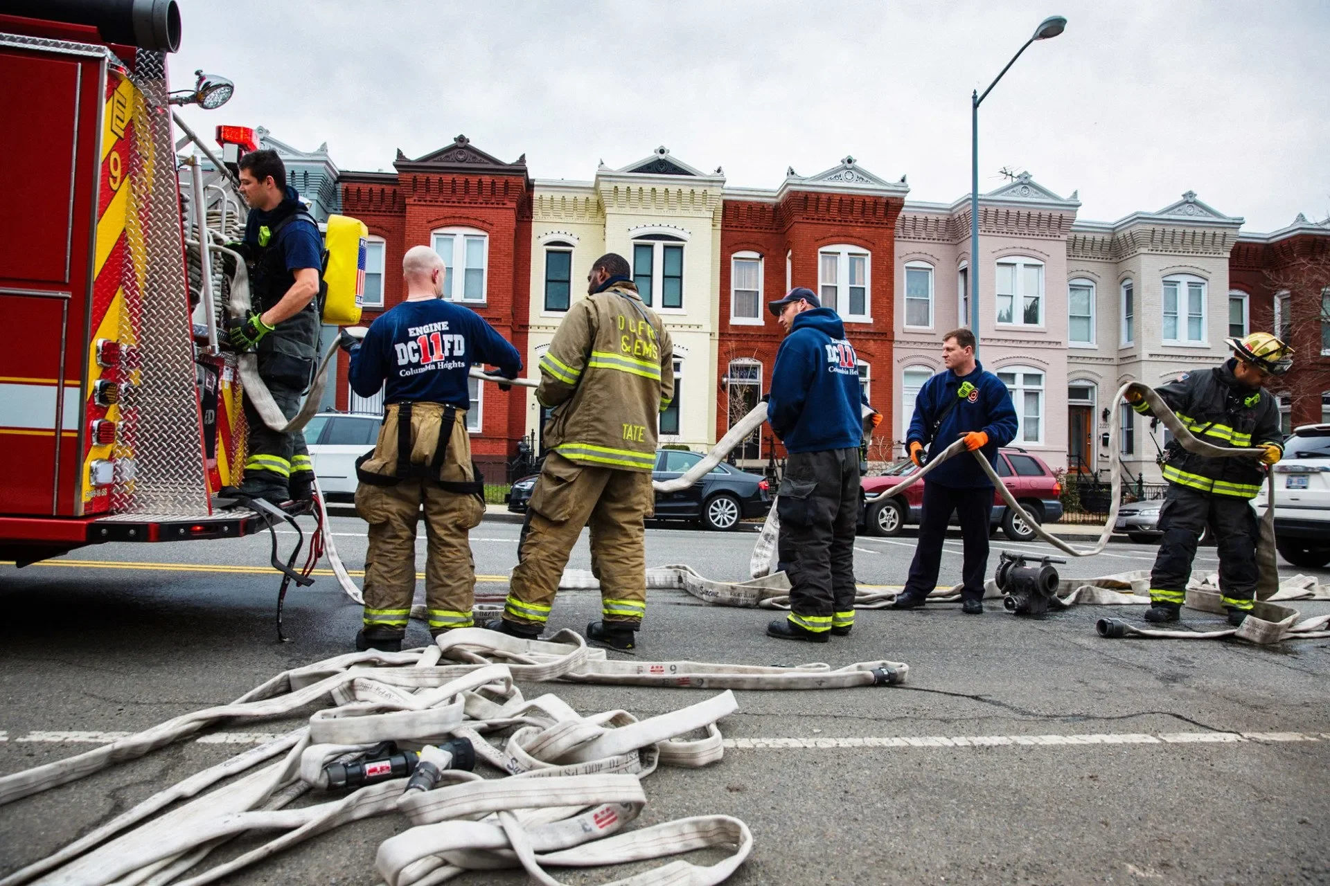 Firefighters from multiple engine and truck companies help load hoses on the back of an engine after distinguishing a fire. Photograph by Erica Baker