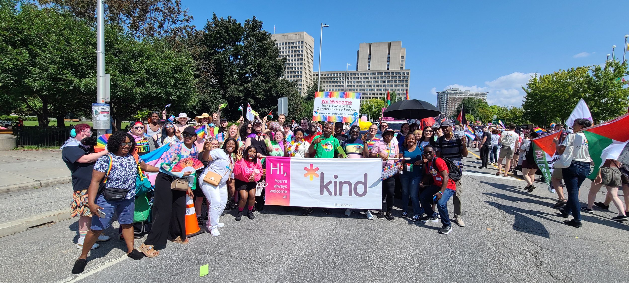 Kind Space members marching together with banners during a local Pride parade.