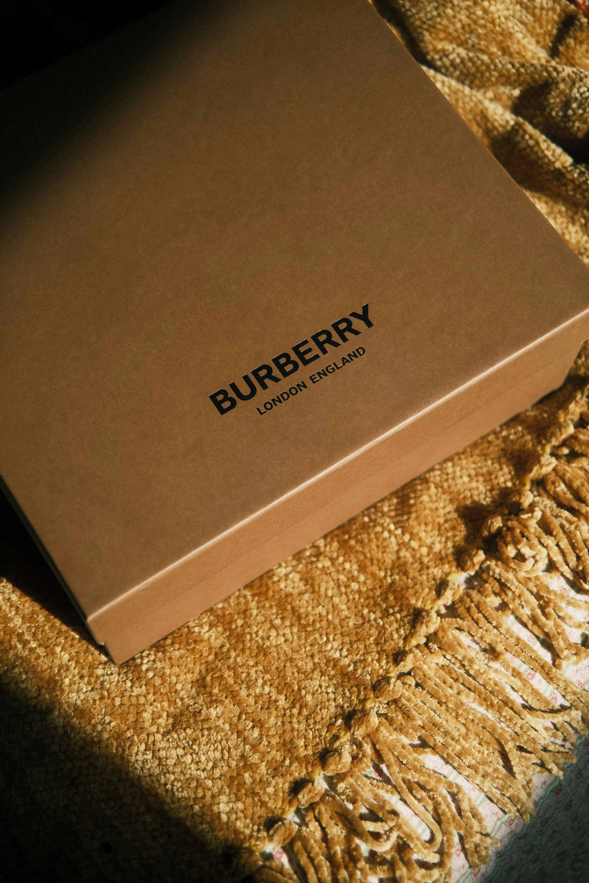 A Burberry box on a textured fabric surface.