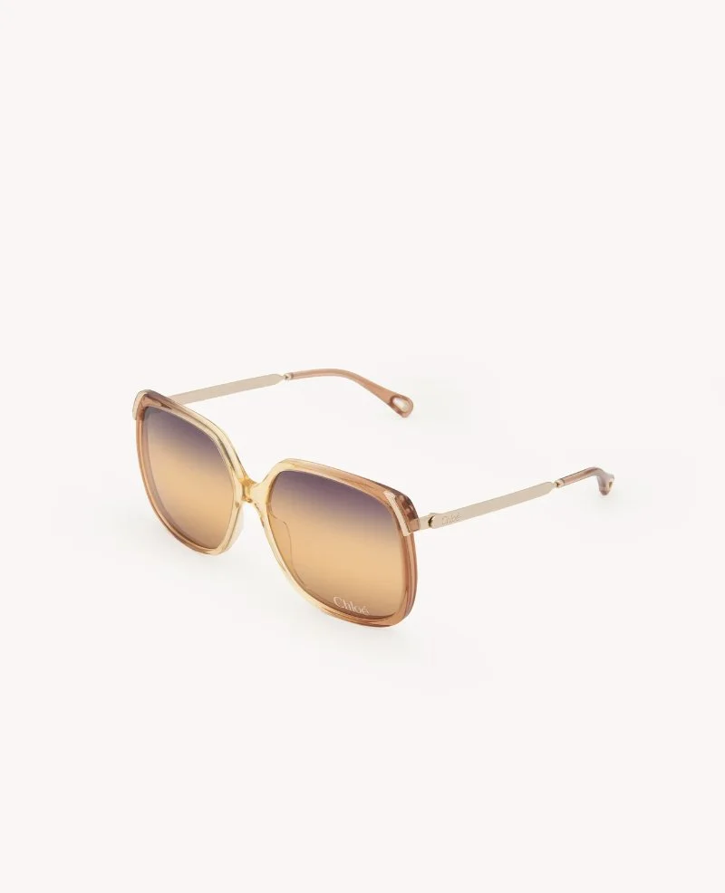 A pair of fashionable sunglasses with gradient brown lenses and a beige and gold frame, positioned on a white background.