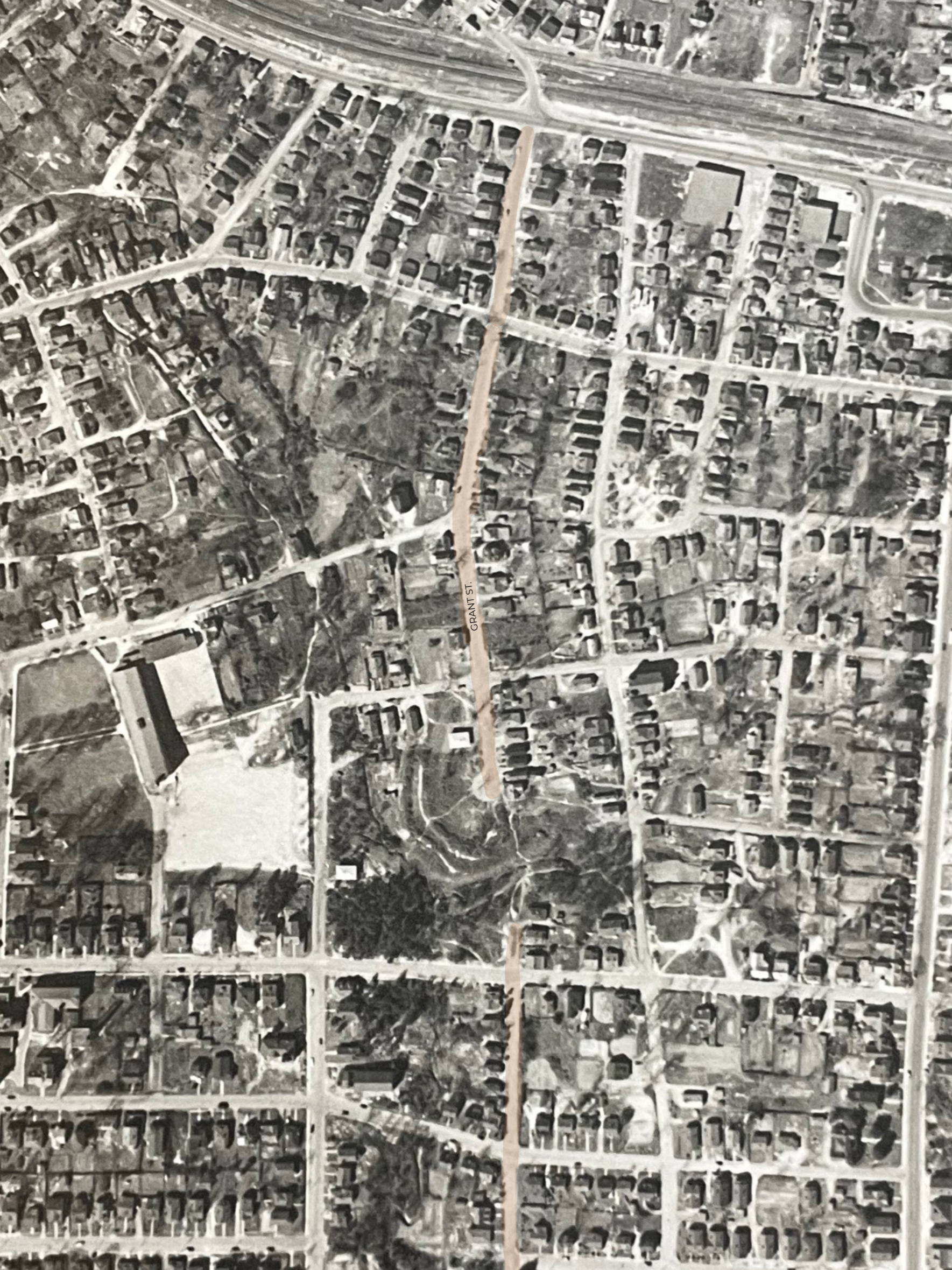 Aerial black and white view of a residential neighborhood with a long vertical street labeled 'Grant St.' running through the center, with houses, roads, and some green areas visible.