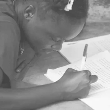 A young girl writing in a notebook with a pen, studying or doing homework.