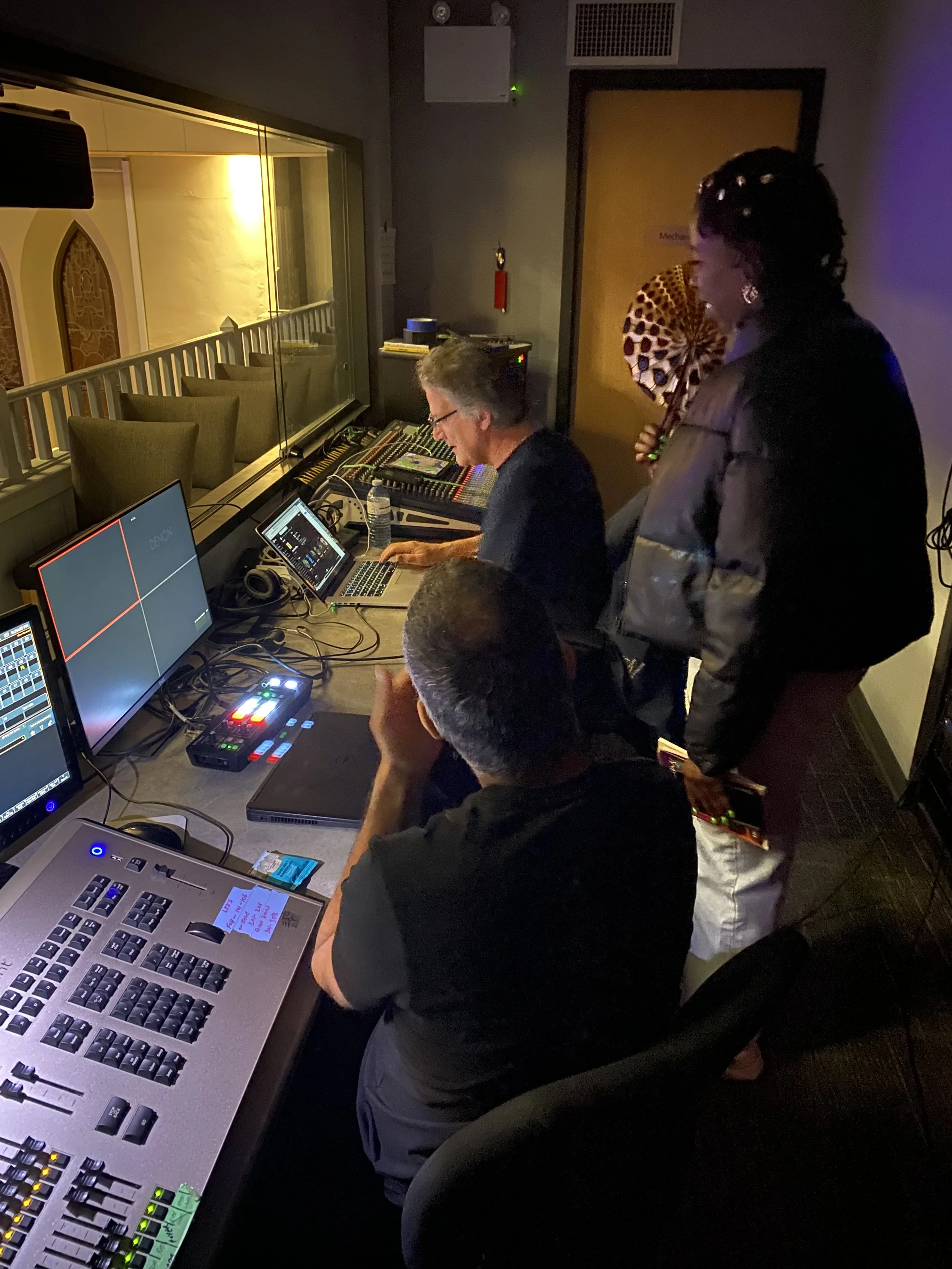 Four people working at a sound mixing console and computers in the St. Francis Centre's control room.
