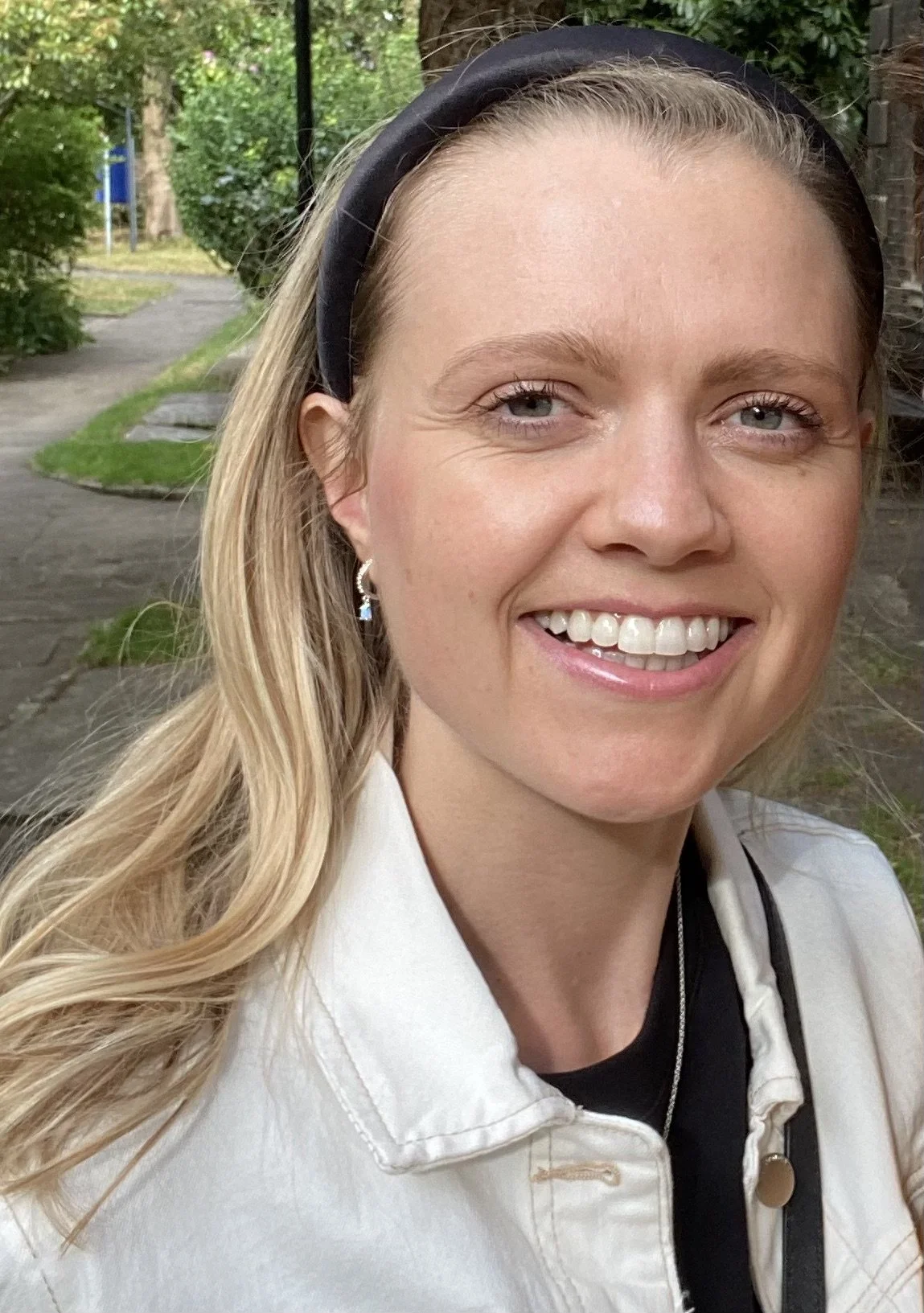 Chloe Plummer, nutritional therapy practitioner, smiling outdoors in a white denim jacket