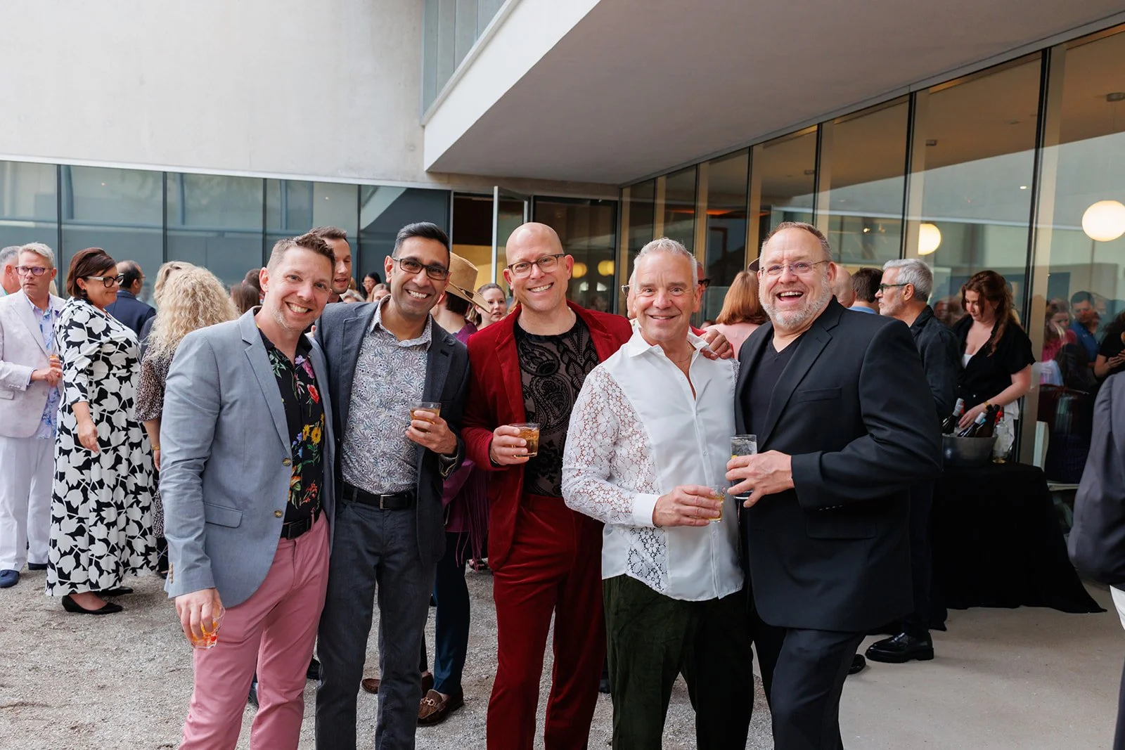 Group of friends smiling and enjoying drinks at an outdoor social event.