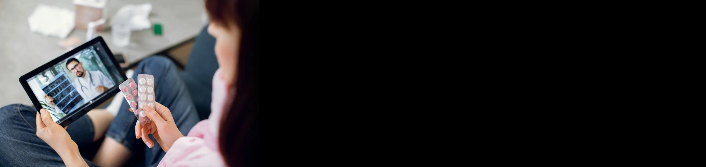 Person watching a video call with a male doctor holding pills.