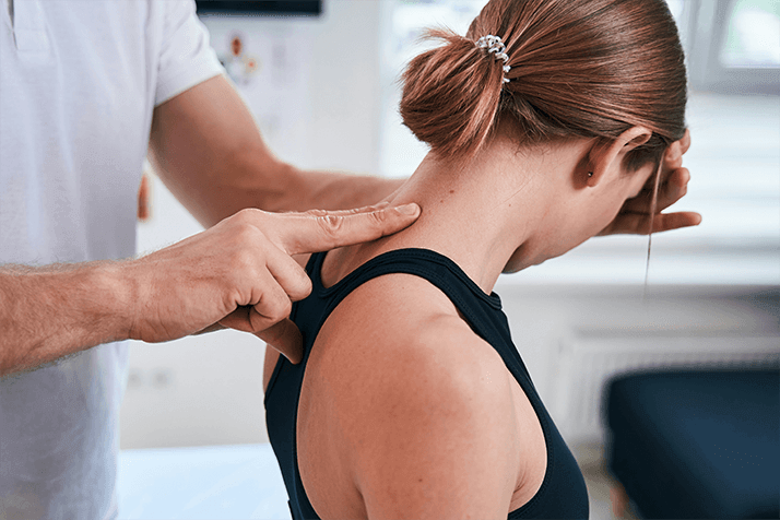 Therapist performing neck massage on a woman in a clinical setting.