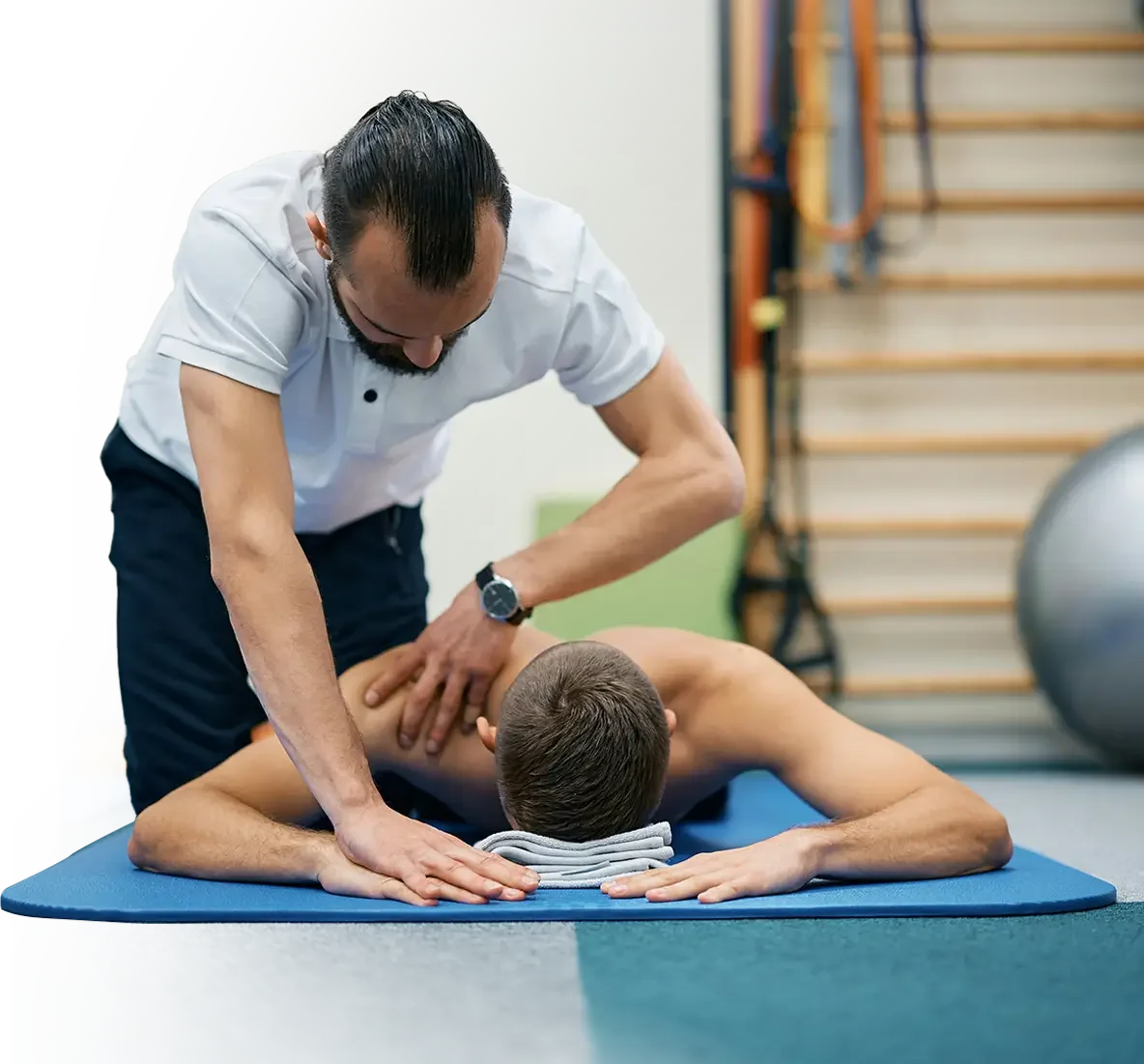 A chiropractor adjusting a young man's back during a session in a clinic or gym.