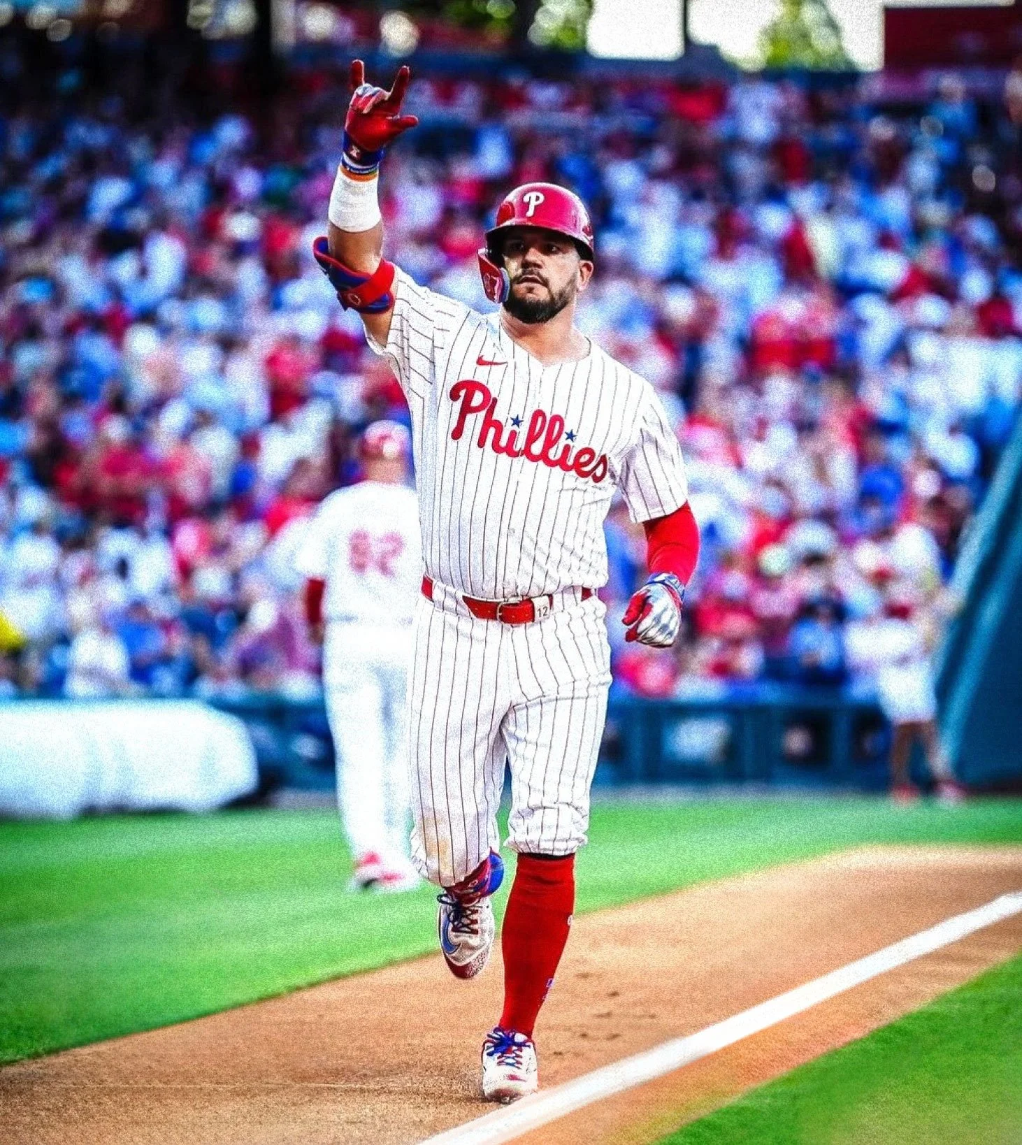 A baseball player in a Philadelphia Phillies uniform running on the field during a game, with a crowd watching in the background.