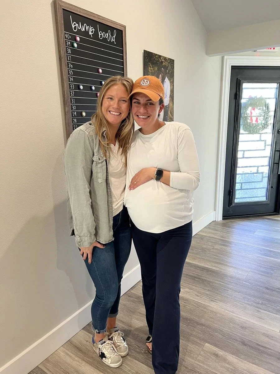 Dr. Kara Rodriguez celebrating with a prenatal patient at the bump board at Social House Chiropractic in Prosper, TX. Webster Certified prenatal care.