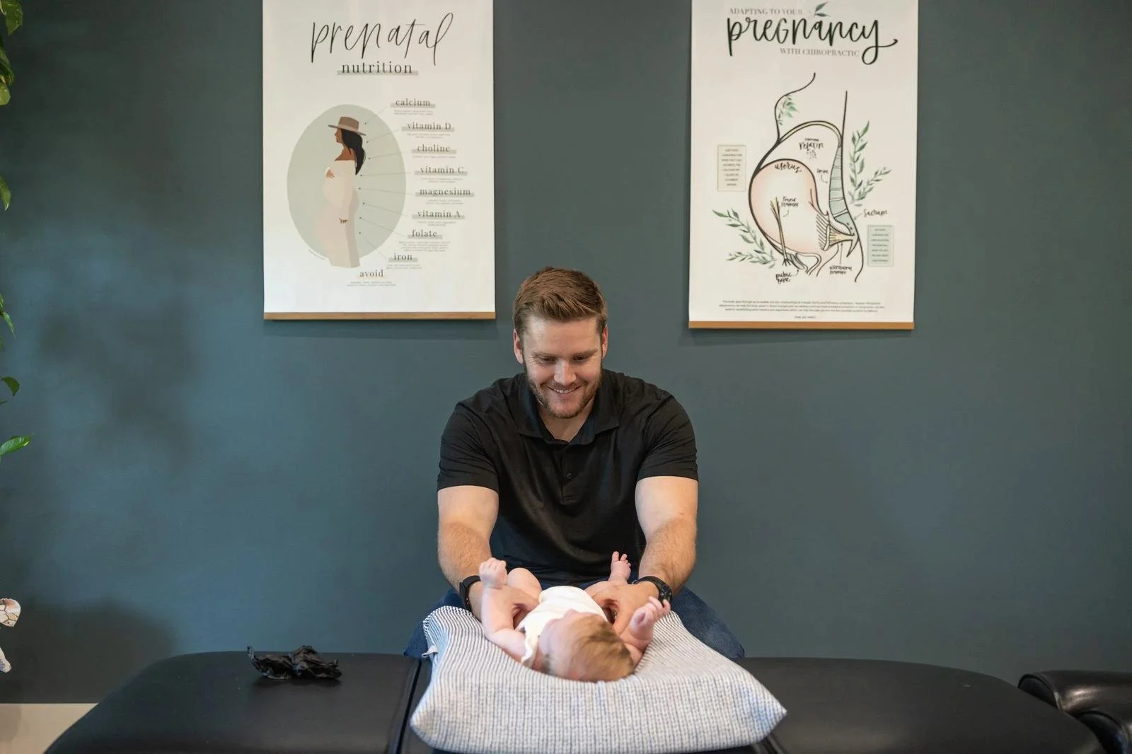 Dr. Collin Walding performing a gentle infant adjustment in the treatment room at Social House Chiropractic in Prosper, TX.