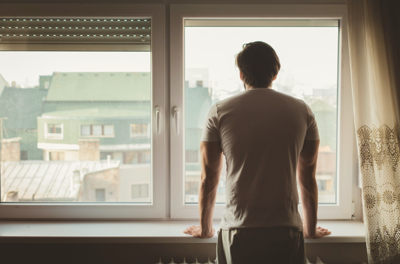 Man looking out window reflecting, representing anxiety and emotional processing in therapy