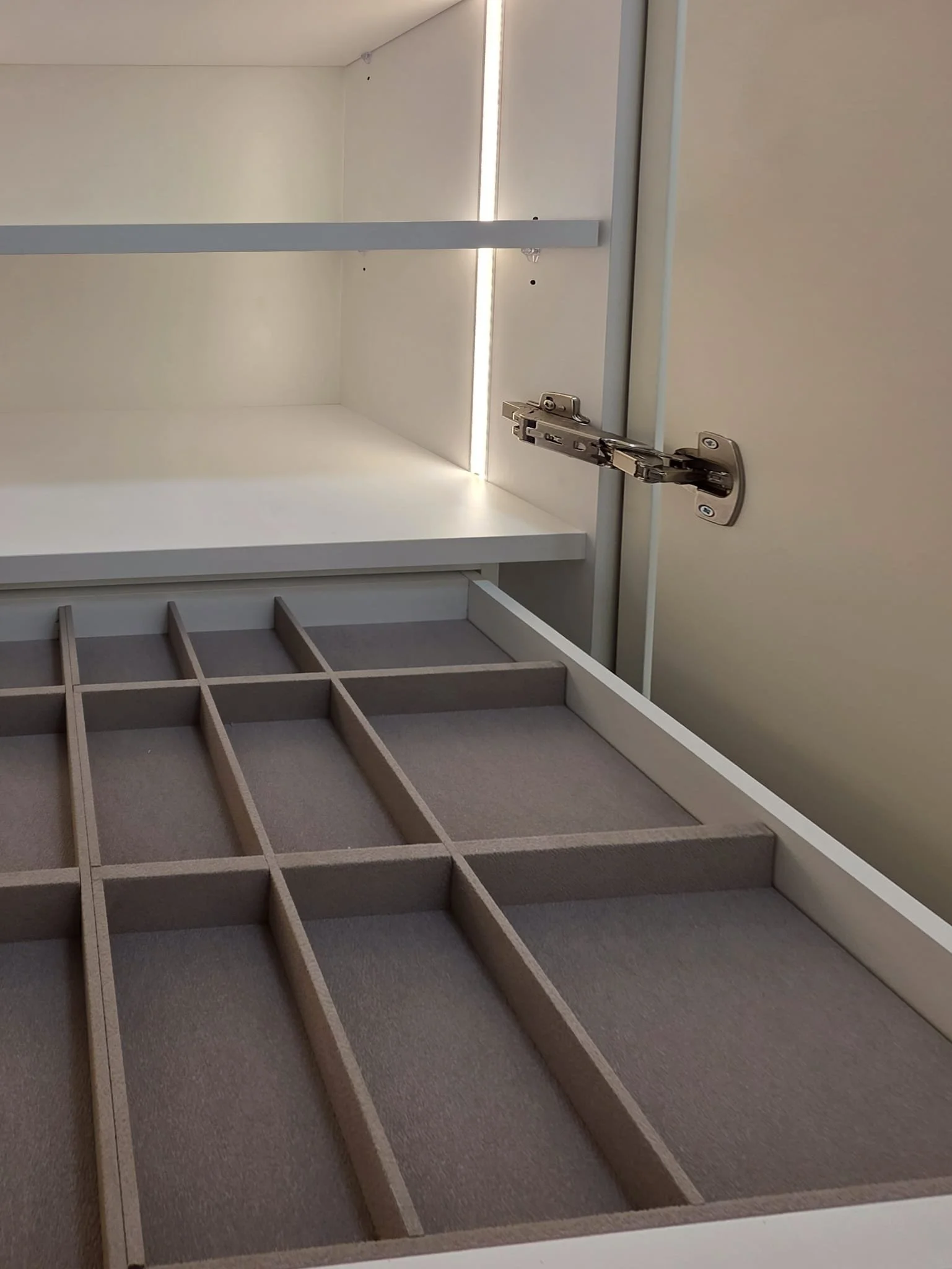 Chambre à coucher moderne avec un lit en bois, quatre oreillers, et une tête de lit noire. Deux fenêtres avec cadres en bois, un tableau avec un arbre et des feuilles, et un tapis blanc sur le sol en bois.