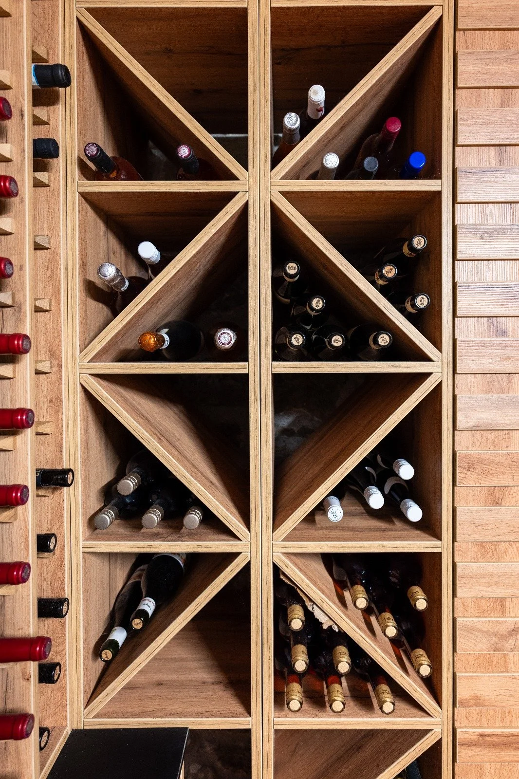 Une cave à vin en bois contenant plusieurs bouteilles de vin rangées horizontalement.