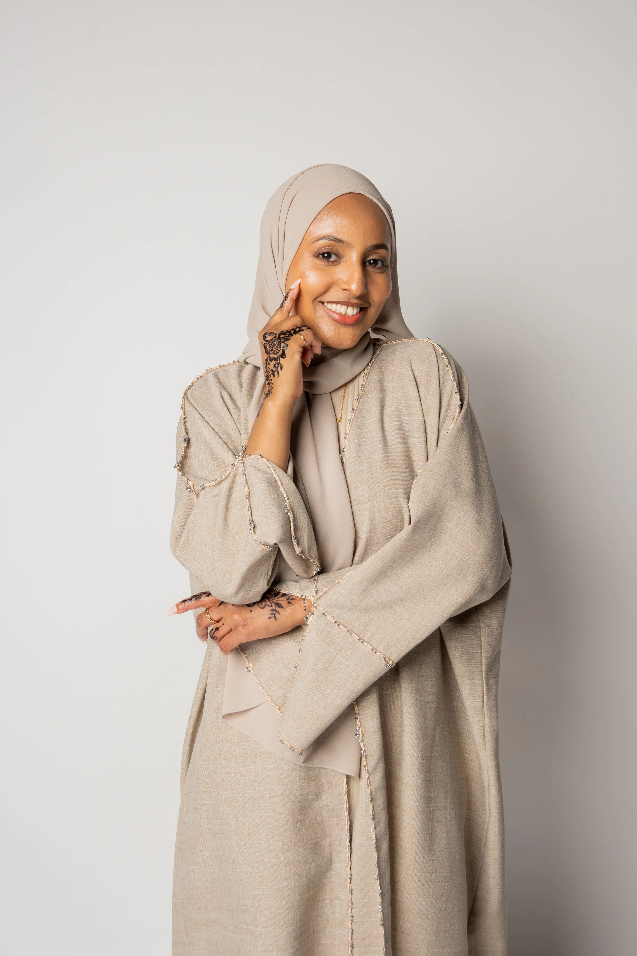 Beige chiffon hijab styled with a modest abaya on a neutral background, showcasing elegant drape and fabric texture.