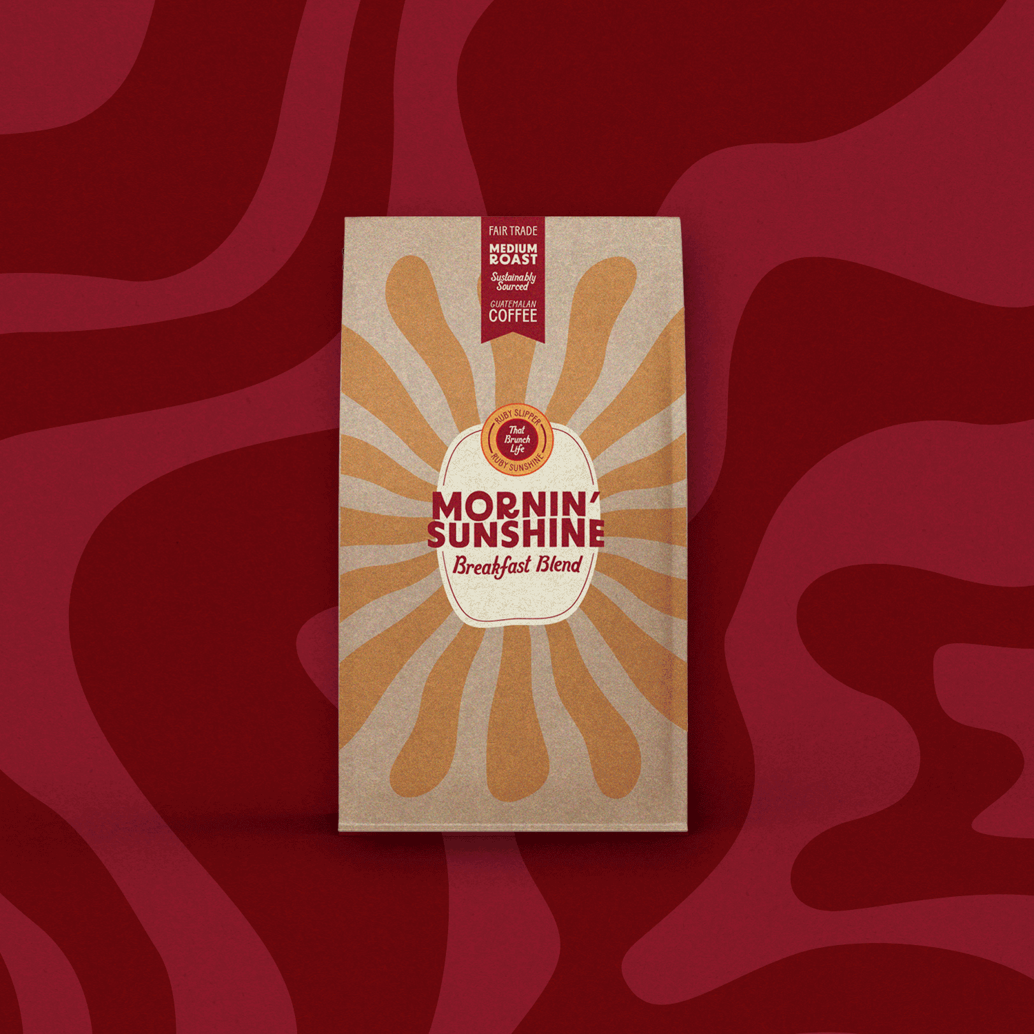 A box of Morning Sunshine Breakfast Blend coffee with a beige and red design featuring radiating rays, set against a red patterned background.
