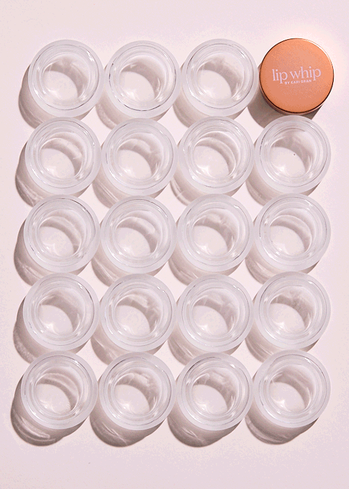 A grid of 16 empty clear containers and a round peach-colored container labeled 'lip whip' by Kari Gran on a white surface.