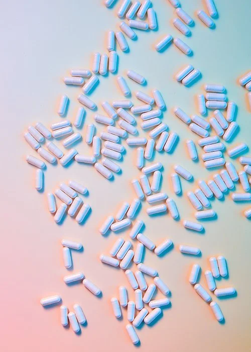 Scattered blue and white capsules on a pastel-colored background