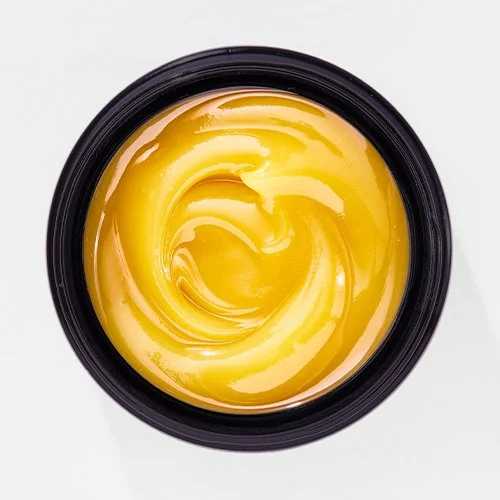 Close-up of a small black container filled with yellow butter or margarine.