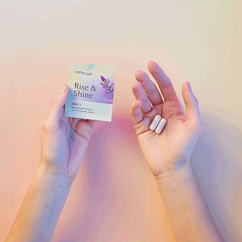 Hands holding a box labeled 'Rise & Shine' and two white tablets.