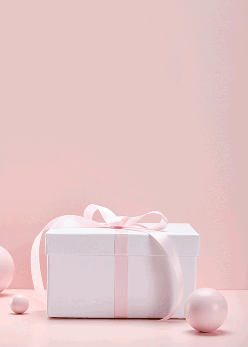 A white gift box with a pink ribbon bow, surrounded by pink and white spheres against a soft pink background.