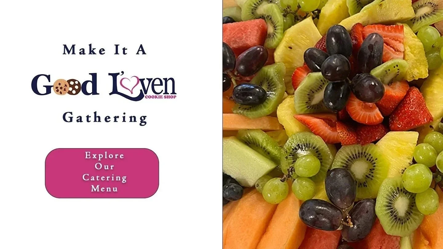 Split image with text on the left side saying 'Make It A Good Love'n Gathering' with a pink button that says 'Explore Our Catering Menu', and on the right side, a close-up of a colorful fruit platter containing strawberries, pineapples, kiwis, grapes