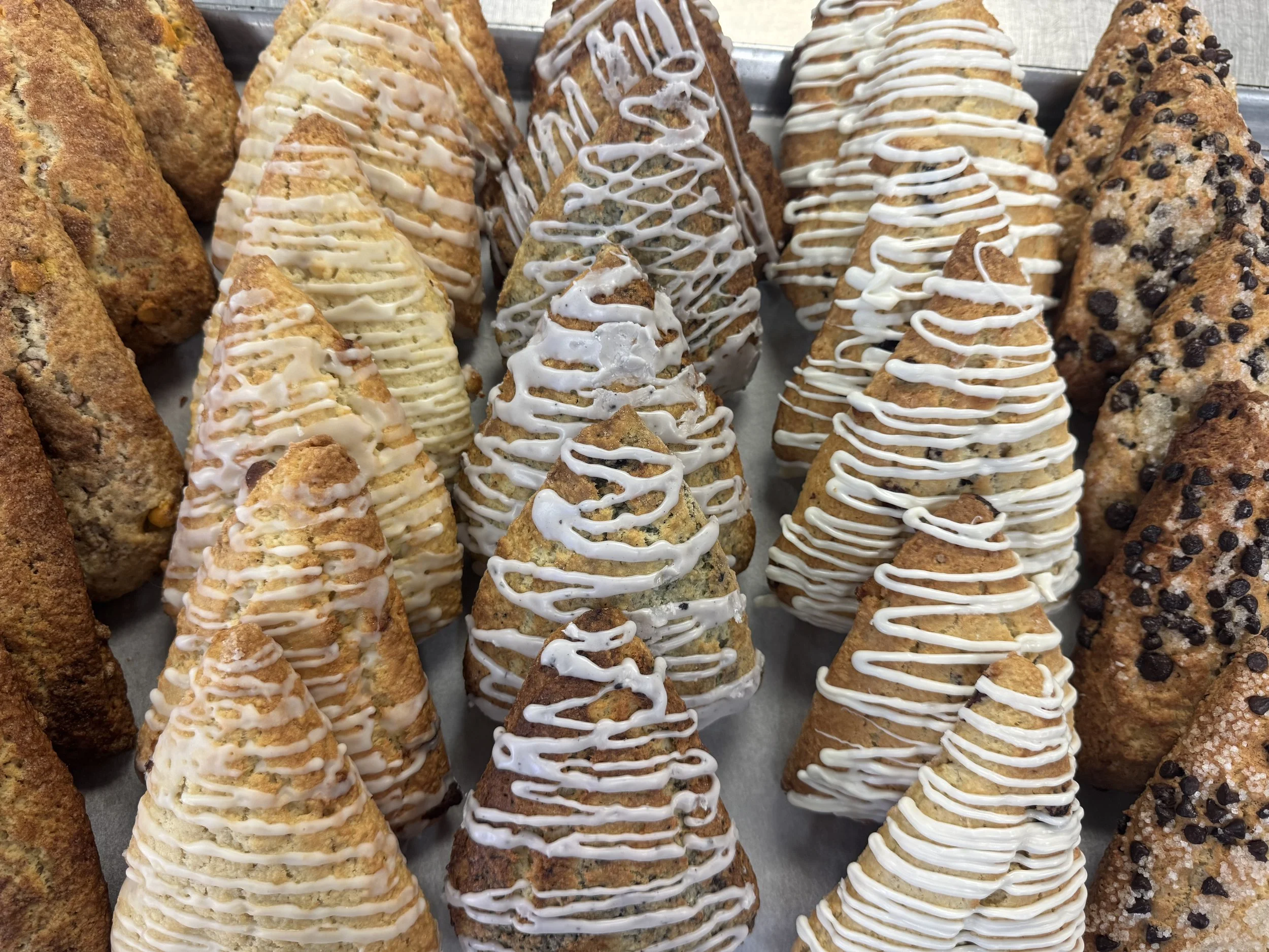 Assorted croissants and scones with drizzled icing and chocolate chips.