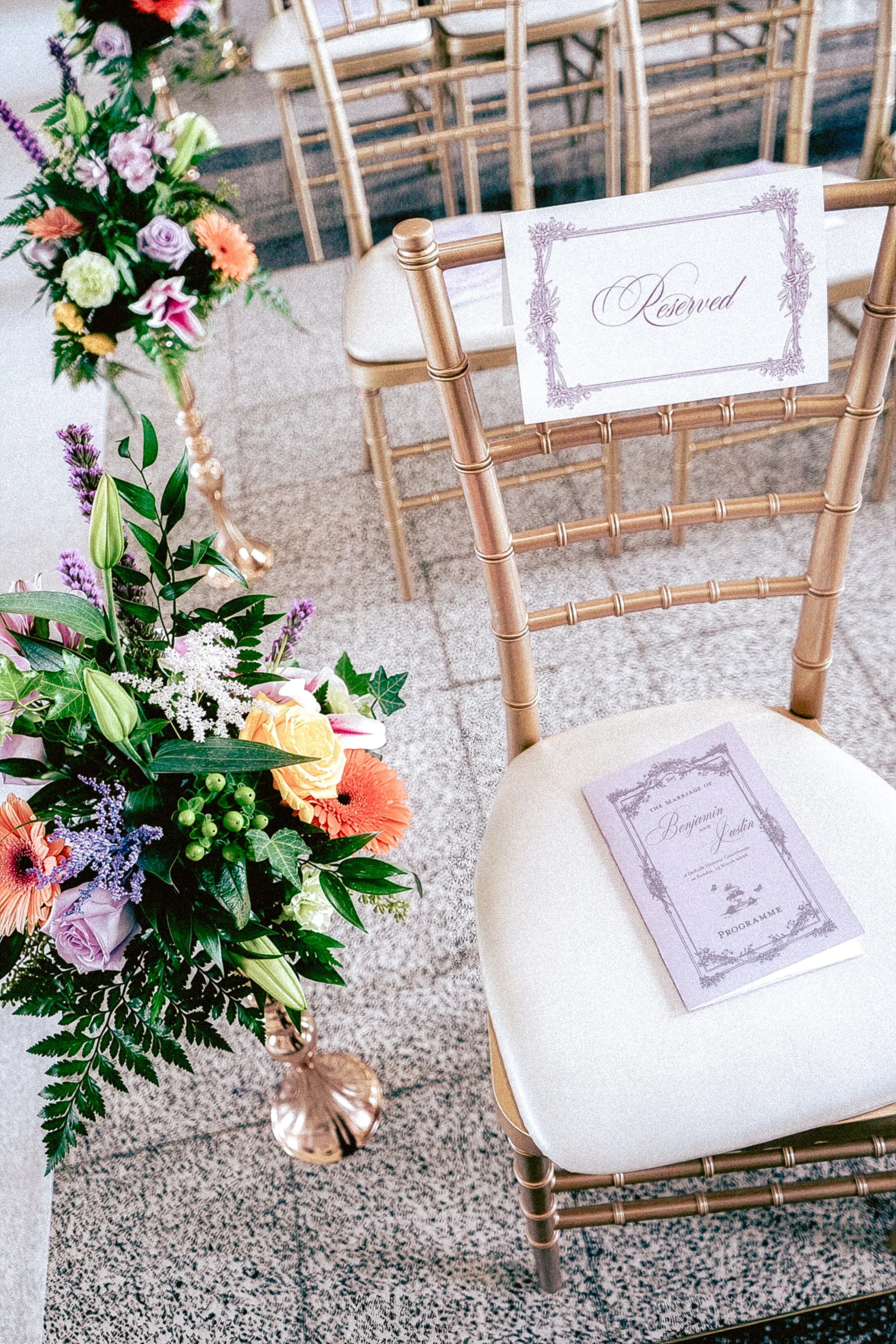 Wedding ceremony setup with gold Chiavari chairs, a floral arrangement, and a reserved sign.