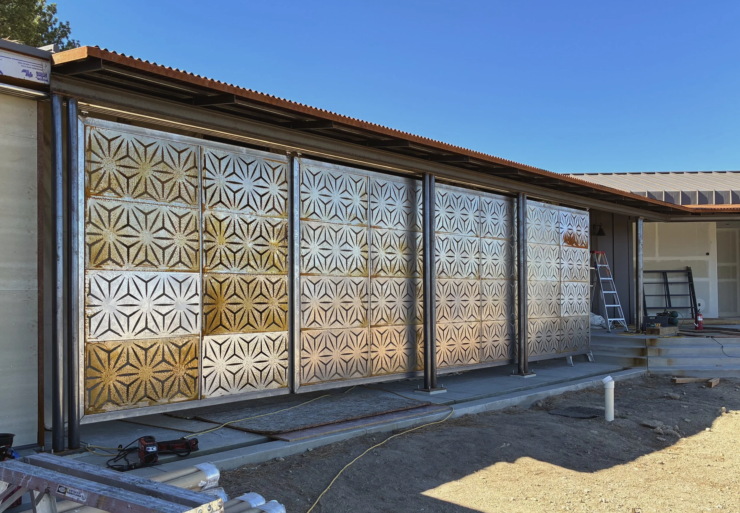 Screening panels, residence, Swall Meadows, CA, 2025. Four 8'x8' steel door panel slide on overhead tracks to screen the glass fascade from unwanted sunlight and wildfire. Scope: design, fabrication, and installation.