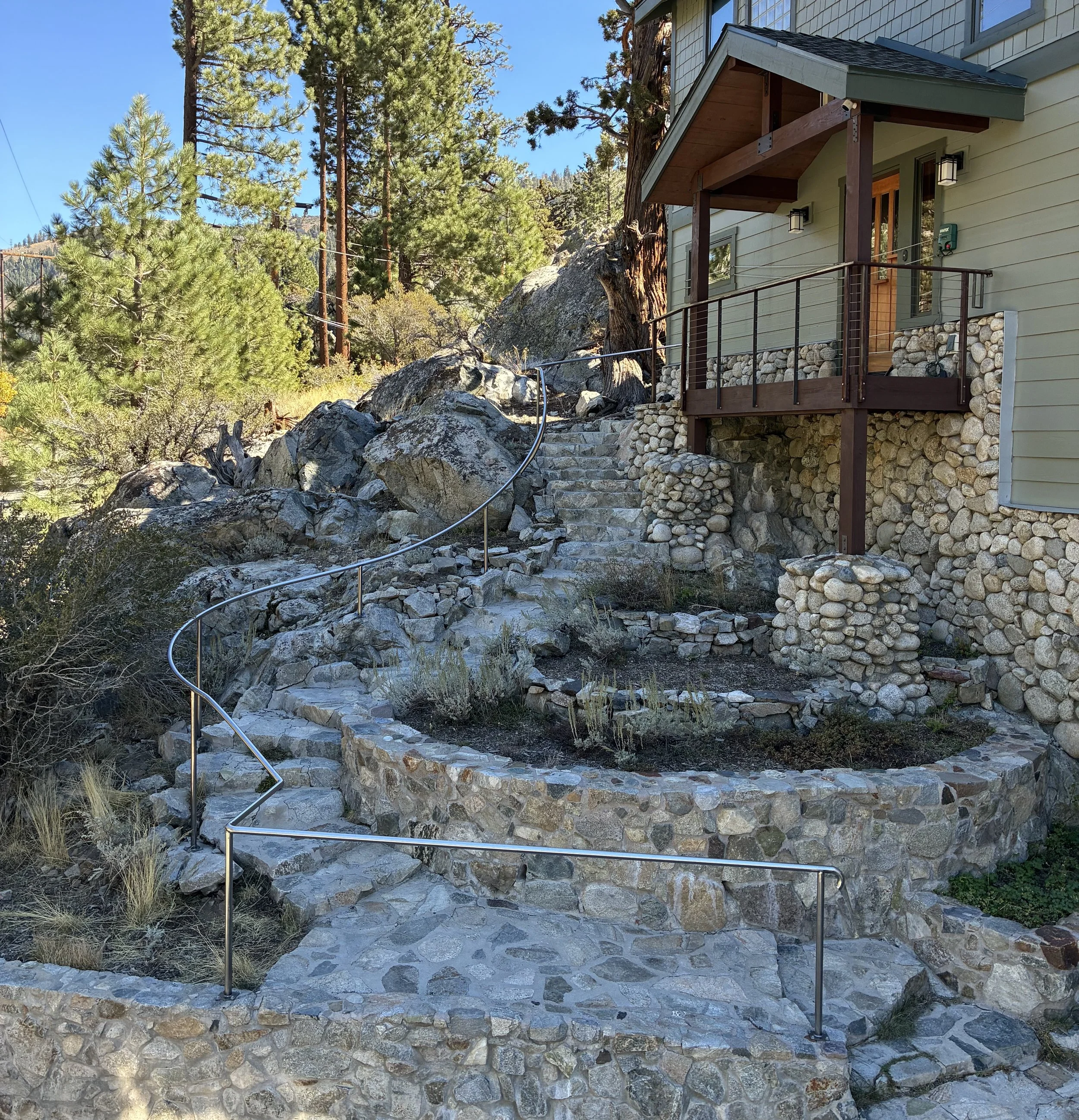 Hand Rail. A 65' seamless steel handrail follows the natural curves of an existing stone staircase. Anchored to existing rock and poured concrete footings.