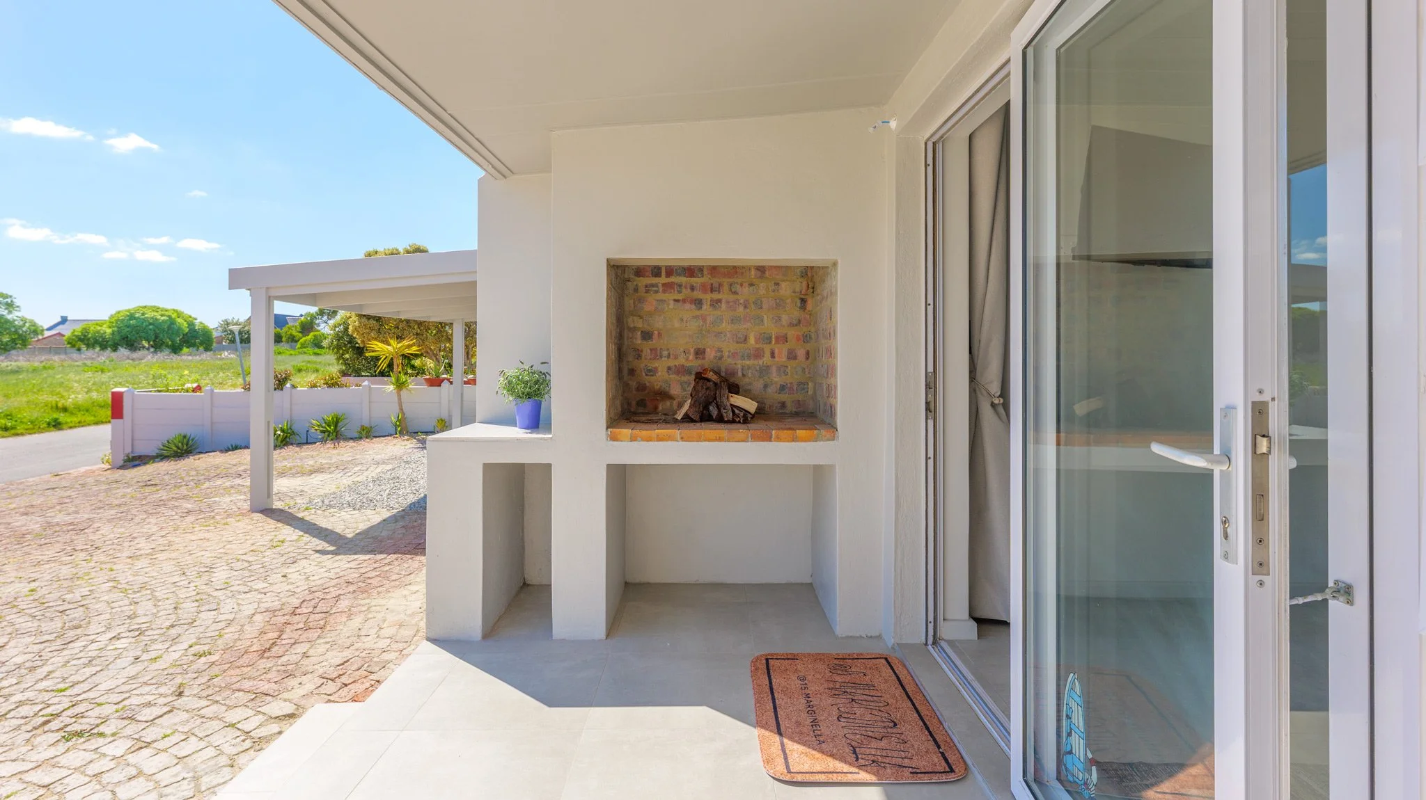 Outdoor patio area with a built-in brick fireplace, a sliding glass door.