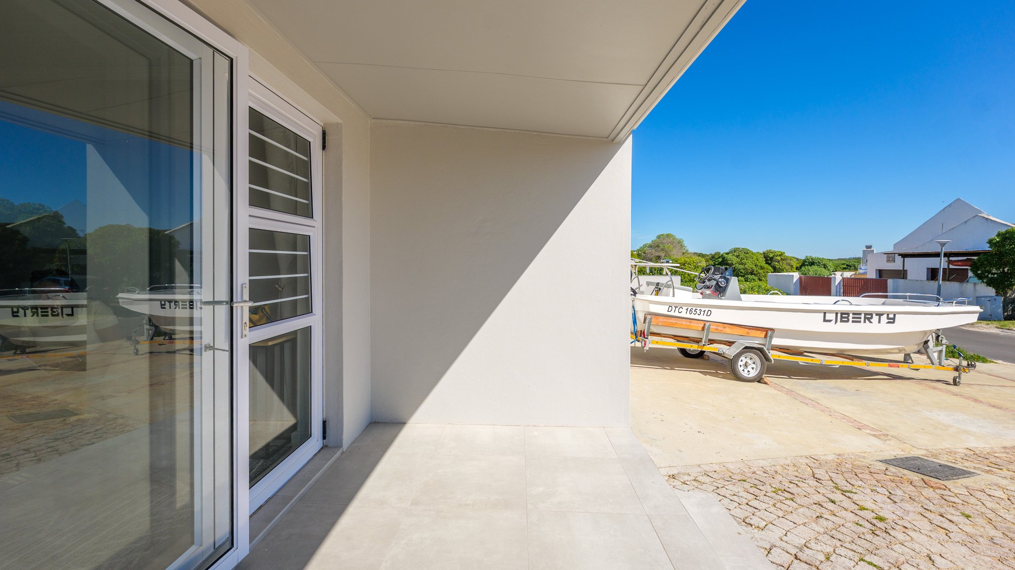 A view from a patio showing a white wall, glass sliding door.