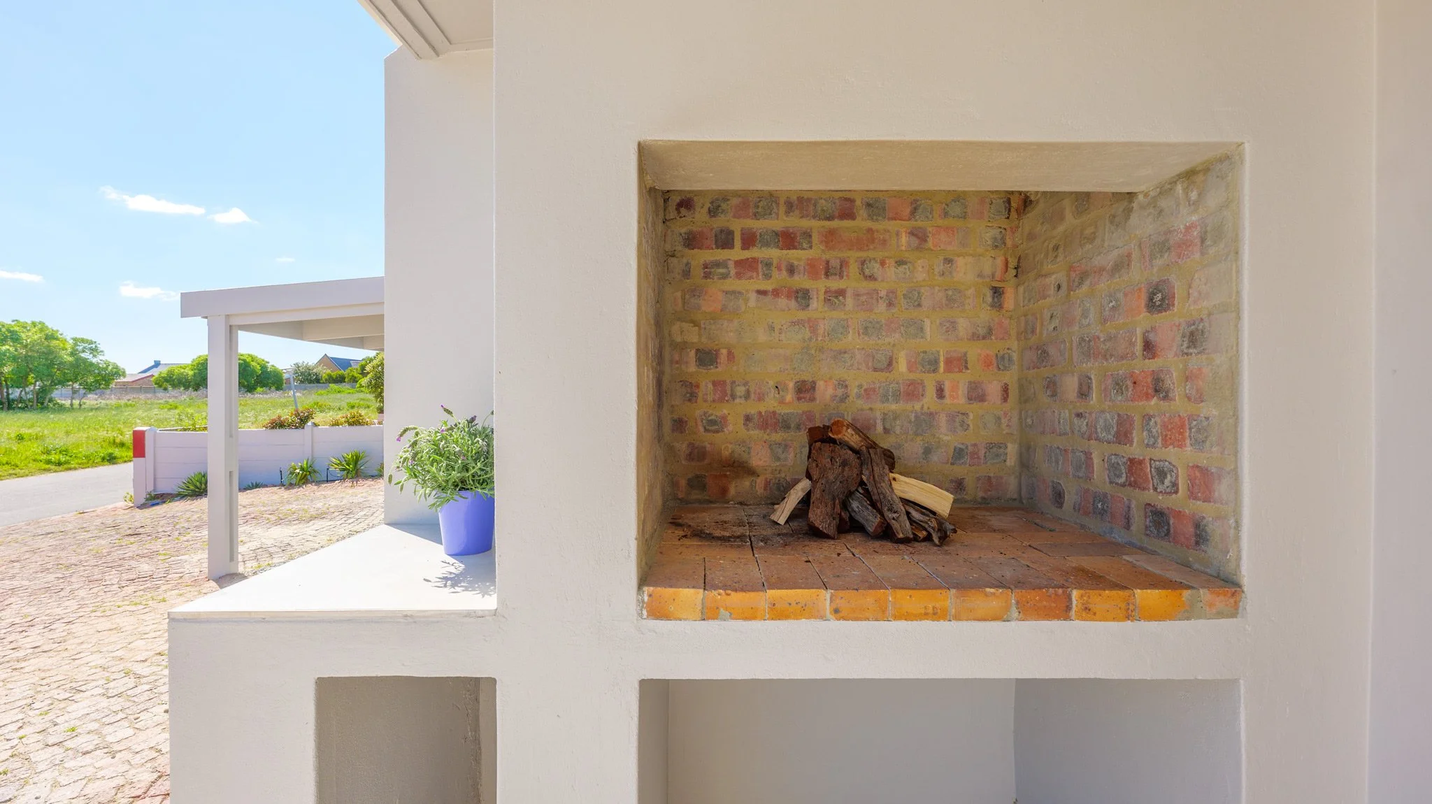 An outdoor brick fireplace with a pile of firewood inside.