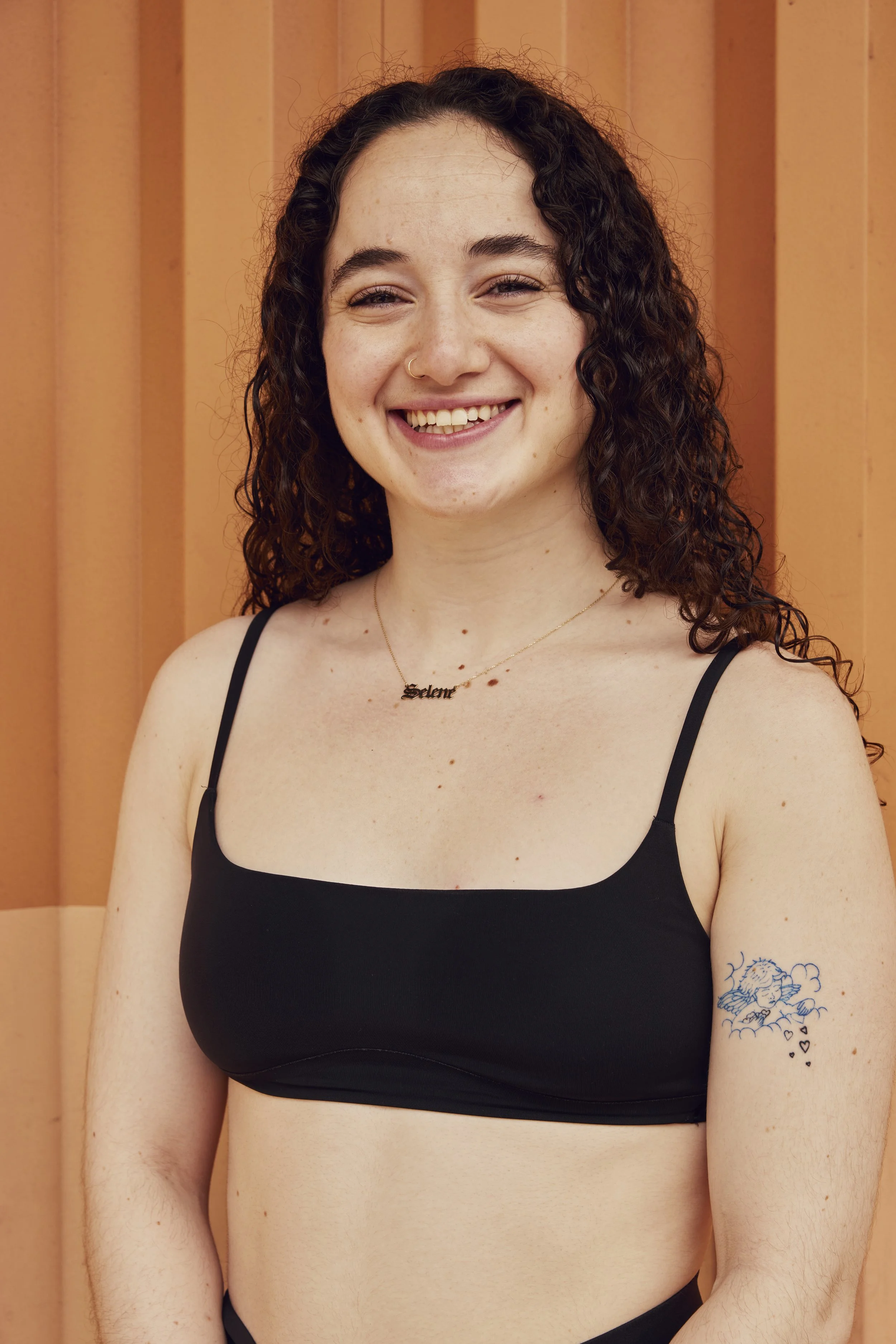 A woman practicing yoga outdoors, balancing on one leg with her hands together in a prayer position, smiling.