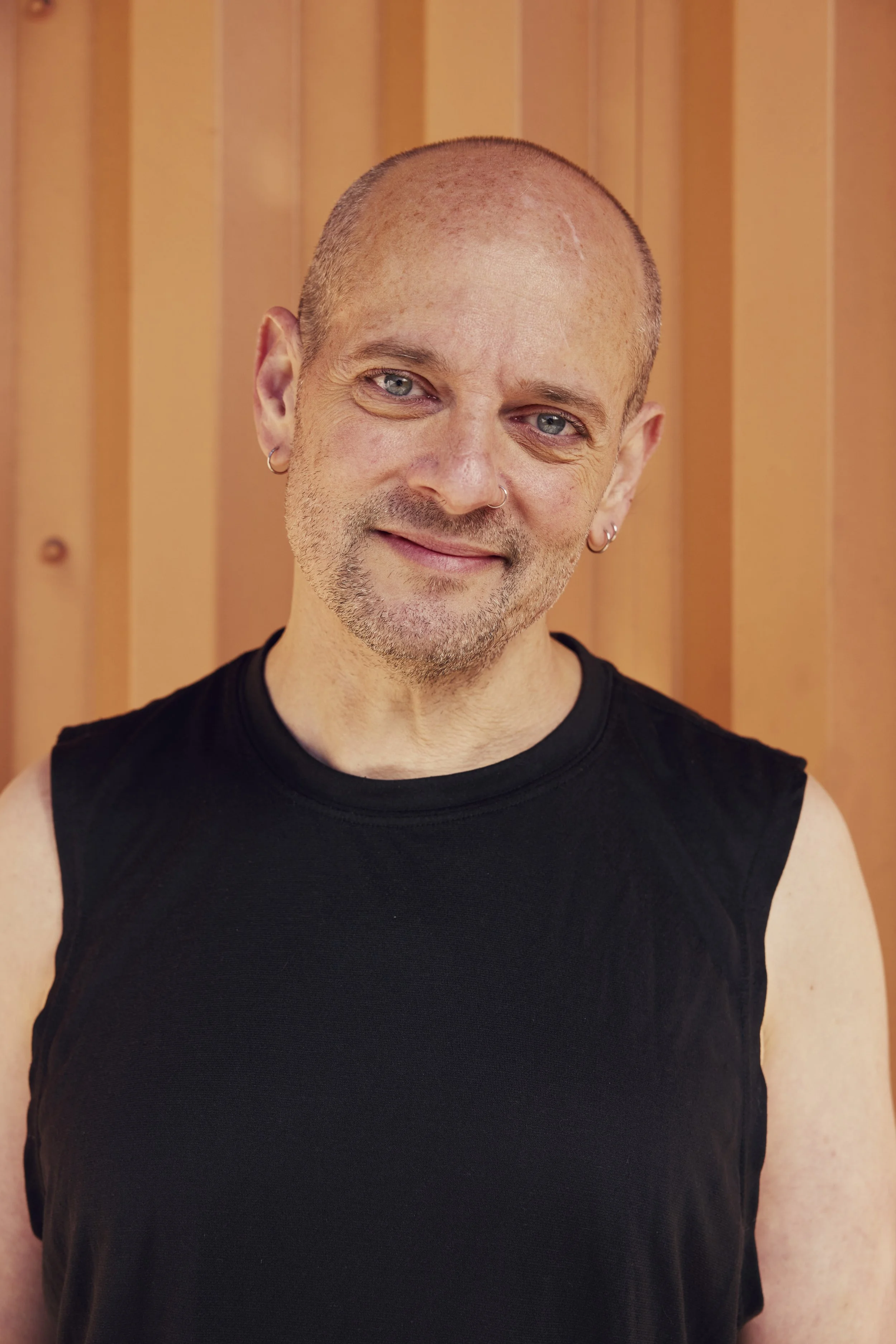 Portrait of a man with short hair, beard, and blue eyes wearing a black turtleneck sweater against a plain background.