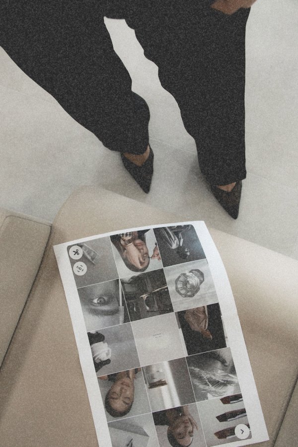 Photo showing a person standing in black pants and black pointed shoes, with a sheet of printed photos on a beige surface nearby.