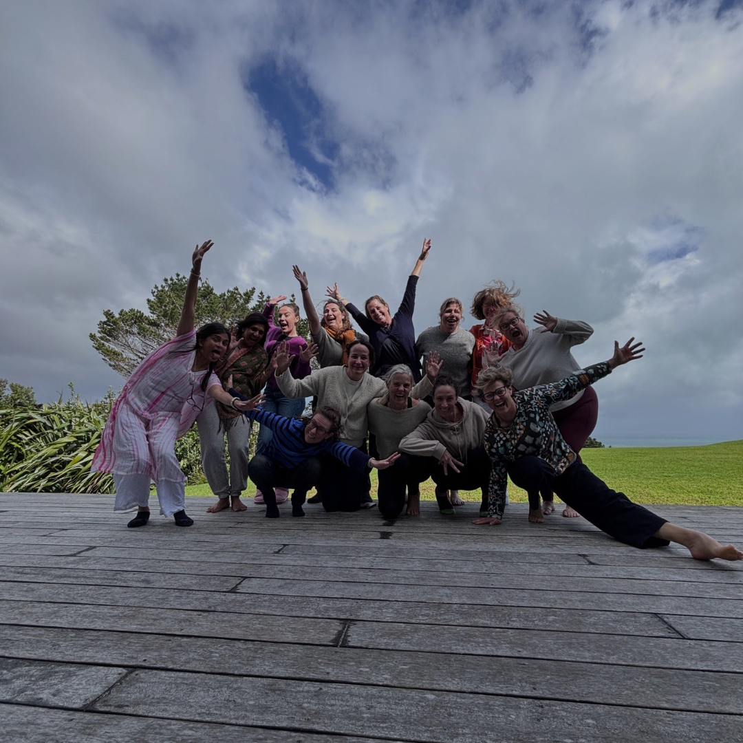 The Sattva Radiance energetic group braving the wind and rain outdoors at Kula Muriwai with the dramatic, skies of the Muriwai West coast above.   