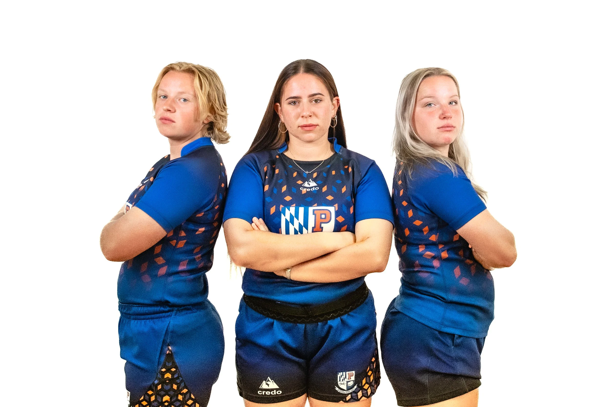 Three female athletes in blue team uniforms standing with arms crossed against a white background.