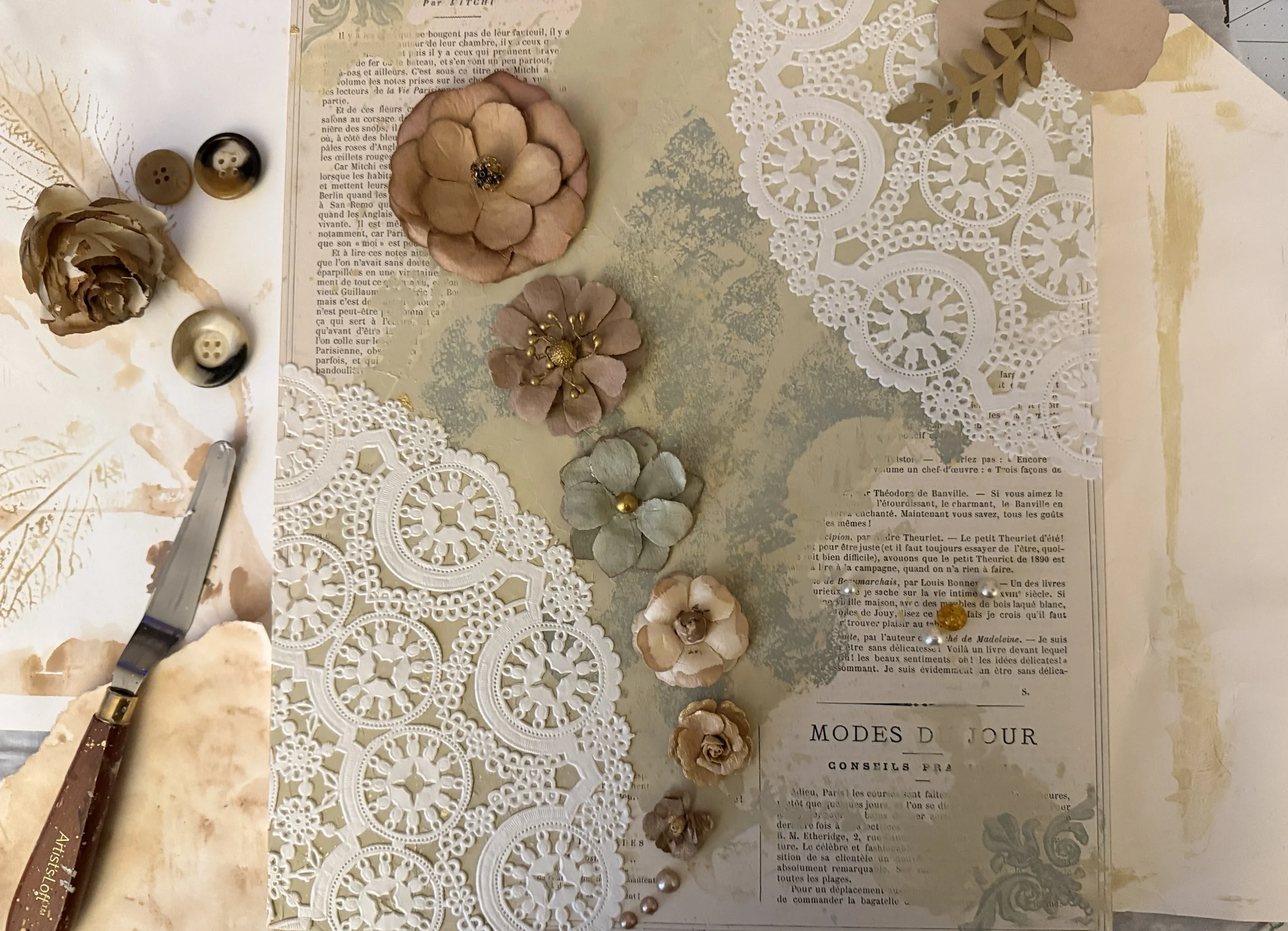 Board with antique newspapers, textured paint, paper flowers, in an art piece.