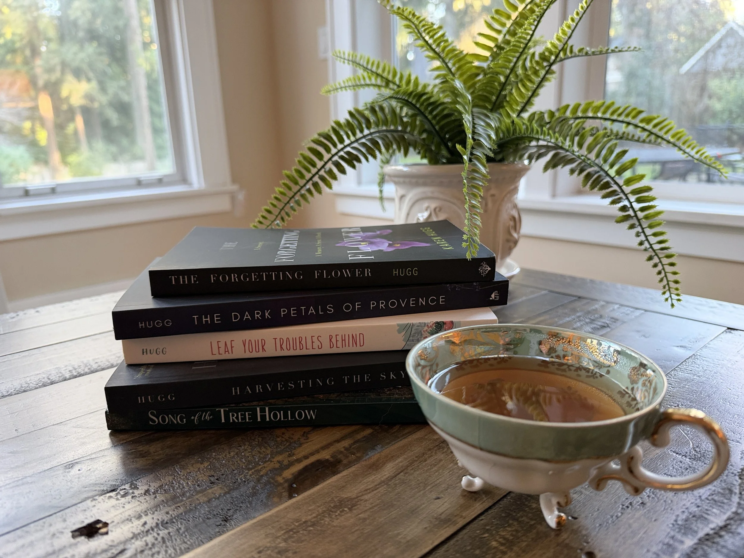 Karen Hugg's books on table with tea and fern