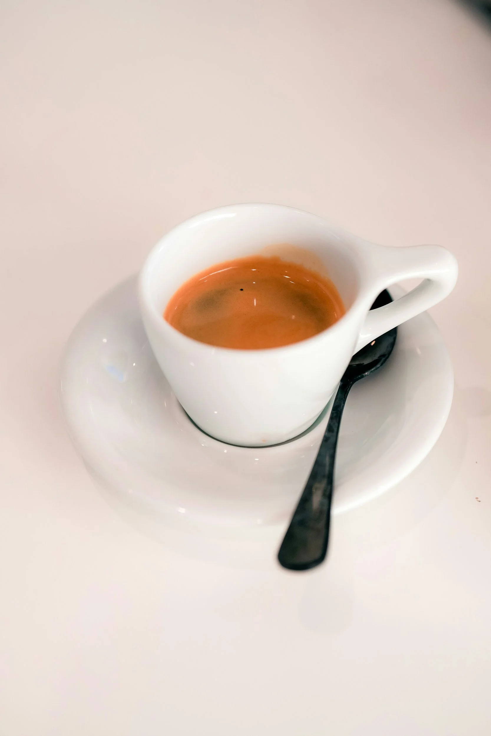 an espresso in a cup with saucer and spoon