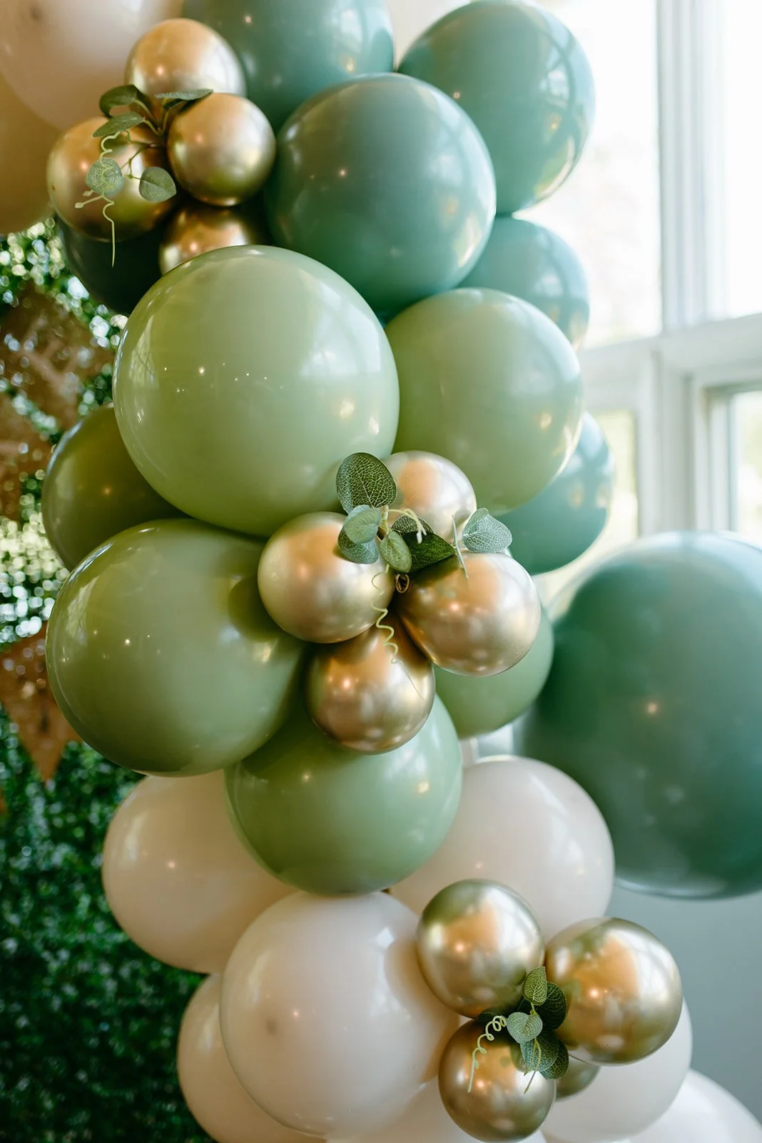 Green, white, and gold balloon arch at a private event. Photo by Robbie and Ryan Photography.